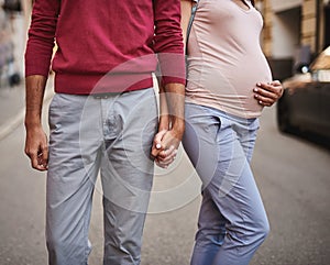 Happy expectant parents holding hands on the street