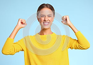 Happy expressive young woman  shouts celebrating victory success and triumph on  blue background
