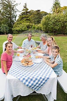 Happy extended family having dinner outdoors at picnic table