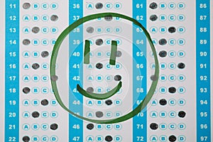 Happy face drawn on answer sheet, top view. Student passing exam