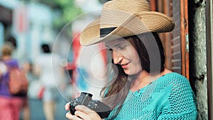 Happy face of female tourist in hat taking photo using professional camera