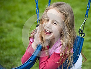 Happy face on a little girl playing with swings