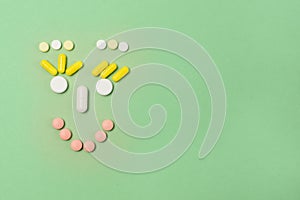 Happy Face Made of Variety Pills on Green Background Top View Copy Space Medical Concept