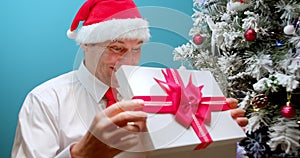 Happy face man delighted with surprise opens box with gifts. Happy smiling dad in Christmas hat Santa Claus receives a