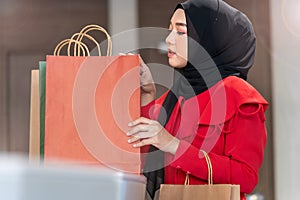 Happy face muslim woman in red dress checking shopping bags. Concept people activity in shopping festival season christmas and new