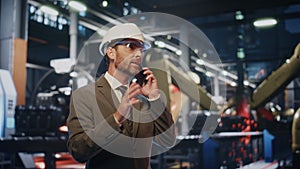 Happy factory specialist calling cellphone on manufacturing facility close up.