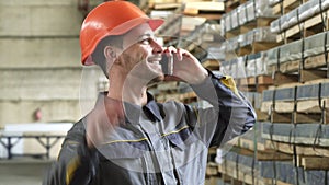 Happy factory worker in a hardhat smiling talking on the phone