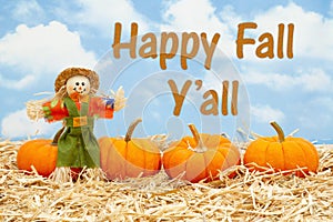 Happy Fall Y`all message with scarecrow and orange pumpkins on straw hay photo