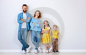 Happy family mother father and children daughter and son  near an   grey blank wall