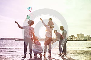 Happy familes flying with kite and having fun on the beach - Parents playing with children outdoor - Love and holidays concept -