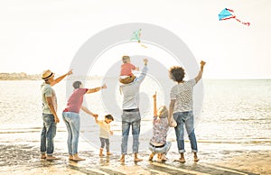 Happy families group with parents and children playing with kite at beach photo