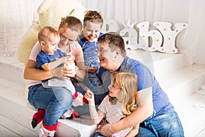 Happy family with 3 children sitting on floor of living room at home