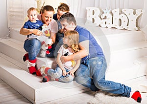 Happy family with 3 children sitting on floor of living room at home