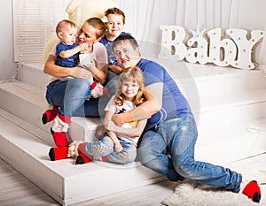 Happy family with 3 children sitting on floor of living room at home