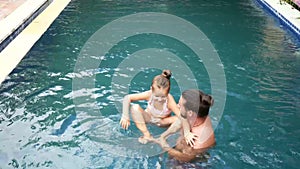 Happy family, active father with little child, adorable toddler daughter, having fun in swimming pool.