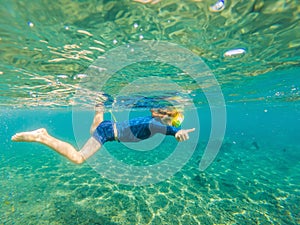 Happy family - active kid in snorkeling mask dive underwater, see tropical fish in coral reef sea pool. Travel adventure