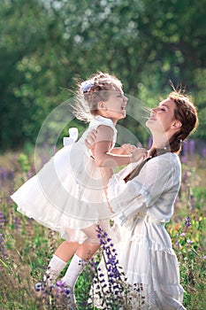 Happy family activities and outdoors lifestyle on a summer meadow with grass and flowers. Little girl child daughter playing and