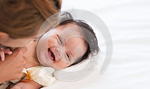 Happy family. Adorable Caucasian newborn 3 months old baby girl having fun playing with mother, lying on bed at home together.