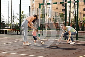 Happy family with adorable little baby playing football