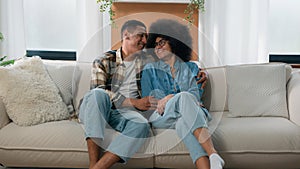 Happy family African American couple in love hugging at couch at home spending time together affectionate bonding man