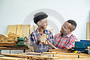 Happy family african american father and son carpenter gather craft a car out of wood and play, family concept to stay at home and