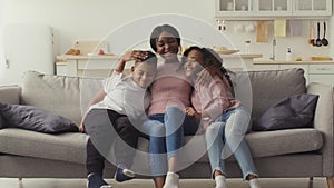 Happy family. African american woman sitting on couch and calling her kids, sun and daughter running and embracing her