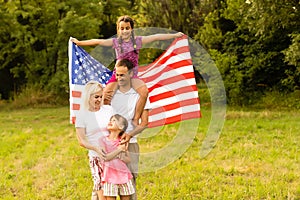 Happy family with the American flag in a wheat field at sunset. Independence Day, 4th of July.