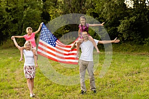 Happy family with the American flag in a wheat field at sunset. Independence Day, 4th of July.