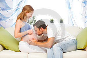 Happy family in anticipation of birth of baby. man kissing belly photo