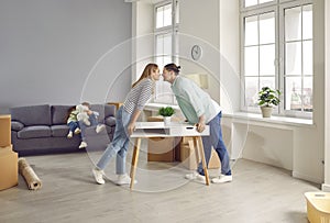 Happy family arranging furniture in a new apartment on moving day and kissing.