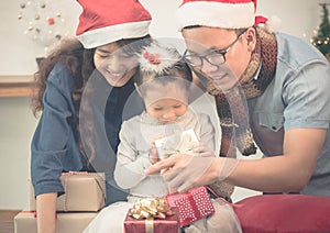 Happy family Asia family wear santa claus hat unwrap Christmas g