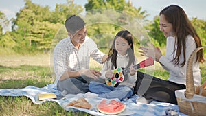 Happy family asian and little girl is playing Ukulele and have enjoyed ourselves together during picnicking