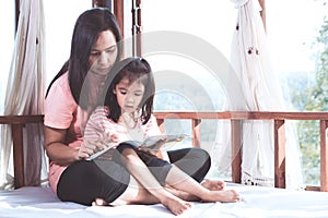 Happy family asian mother and daughter read a book together