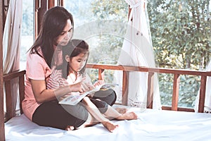 Happy family asian mother and daughter read a book together