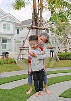 Happy family of Asian sister hugging her little brother in the garden. Young girl child cuddle little boy