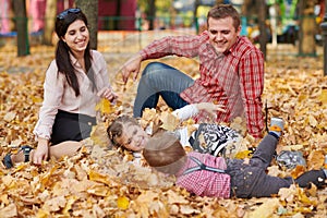 Happy family is in autumn city park. Children and parents. They posing, smiling, playing and having fun. Bright yellow trees