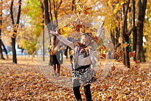 Happy family is in autumn city park. Children and parents running with leaves.. They posing, smiling, playing and having fun. Brig