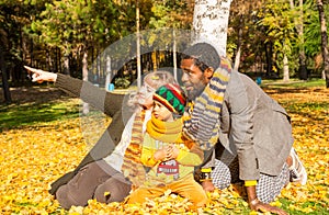 Happy family in autumn park. African American family: black father, mom and child boy on nature in fall.