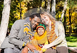 Happy family in autumn park. African American family: black father, mom and child boy on nature in fall.