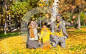 Happy family in autumn park. African American family: black father, mom and child boy on nature in fall.