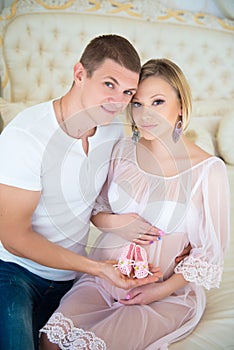 Happy family with baby booties: husband and pregnant wife waiting for a child.