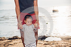 Happy family baby boy and father holding hands walker