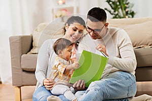 Happy family with baby reading book at home