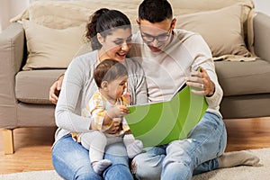 Happy family with baby reading book at home