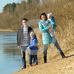 Happy family on the bank of the river in spring near the water.