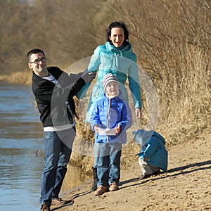 Happy family on the bank of the river in spring near the water