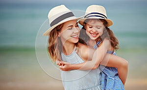 Happy family at beach. mother and child daughter hug at sea