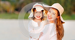 Happy family at beach. mother and child daughter hug at sunset