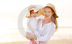 Happy family at beach. mother and child daughter hug at sunset