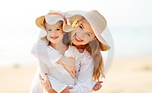 Happy family at beach. mother and child daughter hug at sunset